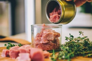 Opened can of corned beef being transferred into an airtight glass container for proper storage